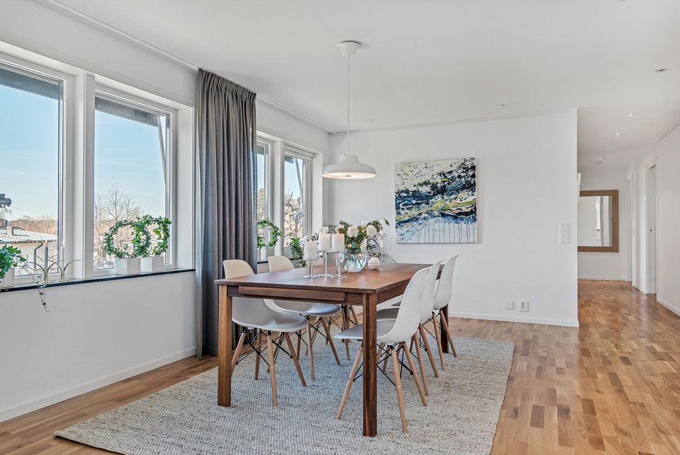 Photo of a mid-sized transitional open plan dining in Stockholm with white walls, light hardwood floors and no fireplace.