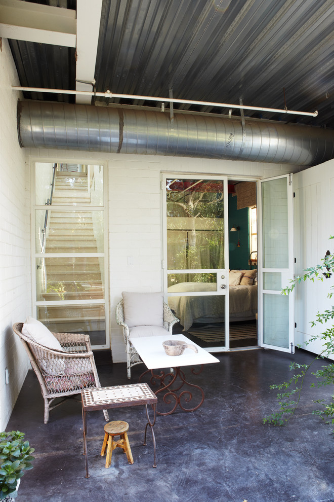 Inspiration for a small industrial side yard patio in Orange County with concrete pavers and a roof extension.
