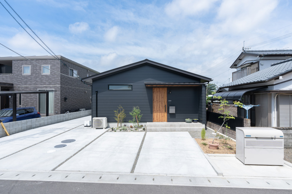 На фото: одноэтажный, черный частный загородный дом в стиле модернизм с двускатной крышей, металлической крышей и черной крышей с