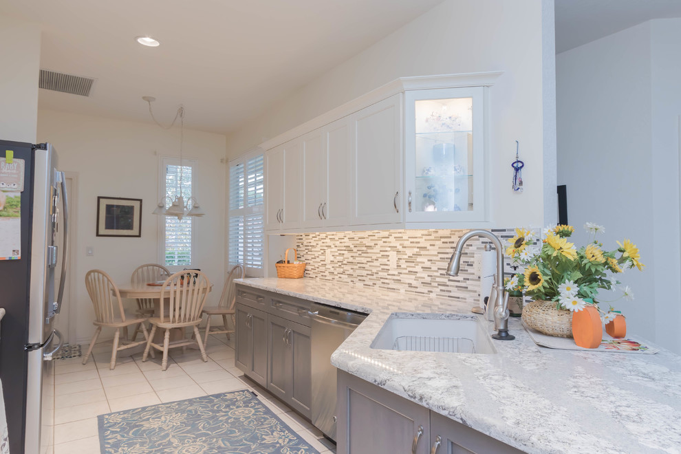 Example of a mid-sized transitional galley ceramic tile and white floor eat-in kitchen design with an undermount sink, shaker cabinets, gray cabinets, quartz countertops, gray backsplash, glass tile backsplash and stainless steel appliances