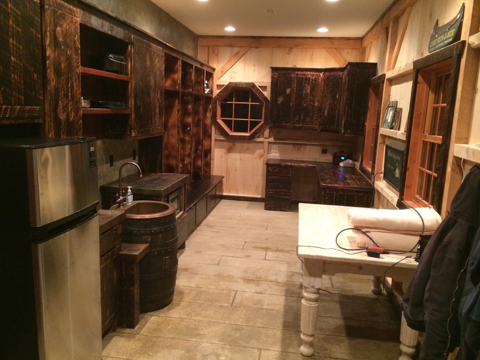 Open concept kitchen - small rustic single-wall beige floor and light wood floor open concept kitchen idea with no island, a farmhouse sink, dark wood cabinets, brown countertops, brown backsplash and stainless steel appliances