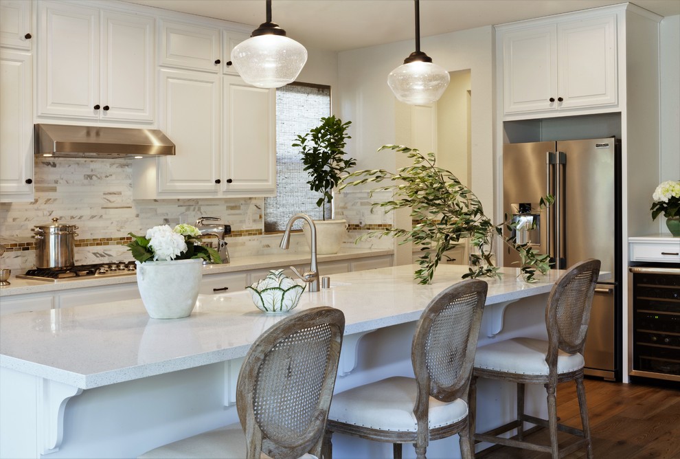 This is an example of a mid-sized beach style galley eat-in kitchen in San Francisco with a farmhouse sink, raised-panel cabinets, white cabinets, terrazzo benchtops, white splashback, marble splashback, stainless steel appliances, medium hardwood floors, with island and brown floor.