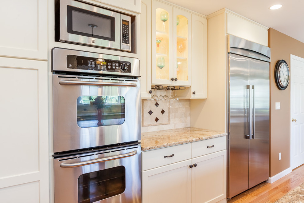 Inspiration for a transitional eat-in kitchen remodel in Boston with furniture-like cabinets, yellow cabinets, granite countertops, beige backsplash, stone tile backsplash and stainless steel appliances