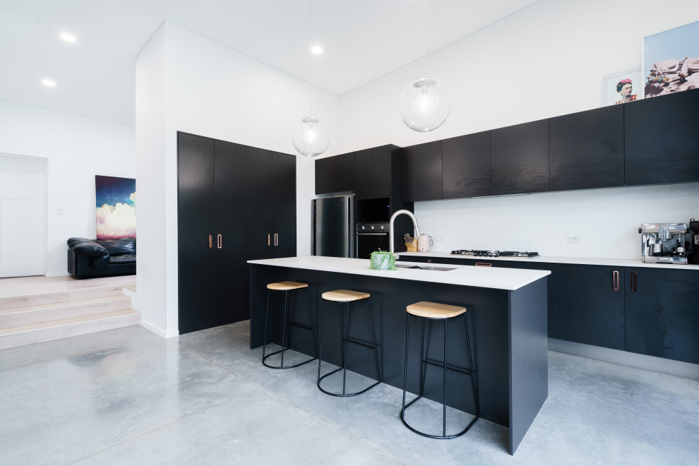 Design ideas for a contemporary kitchen in Sydney with an undermount sink, flat-panel cabinets, black cabinets, white splashback, stainless steel appliances, concrete floors, with island, grey floor, white benchtop and vaulted.