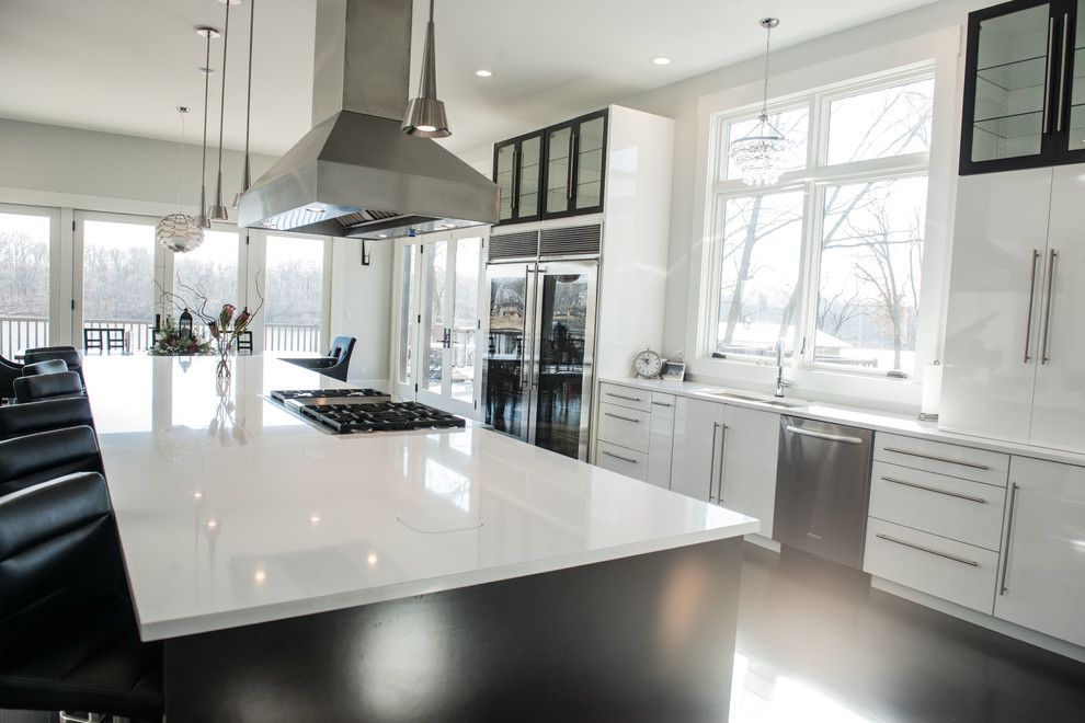 This is an example of an expansive modern galley open plan kitchen in Chicago with a double-bowl sink, flat-panel cabinets, white cabinets, quartz benchtops, stainless steel appliances, dark hardwood floors and with island.