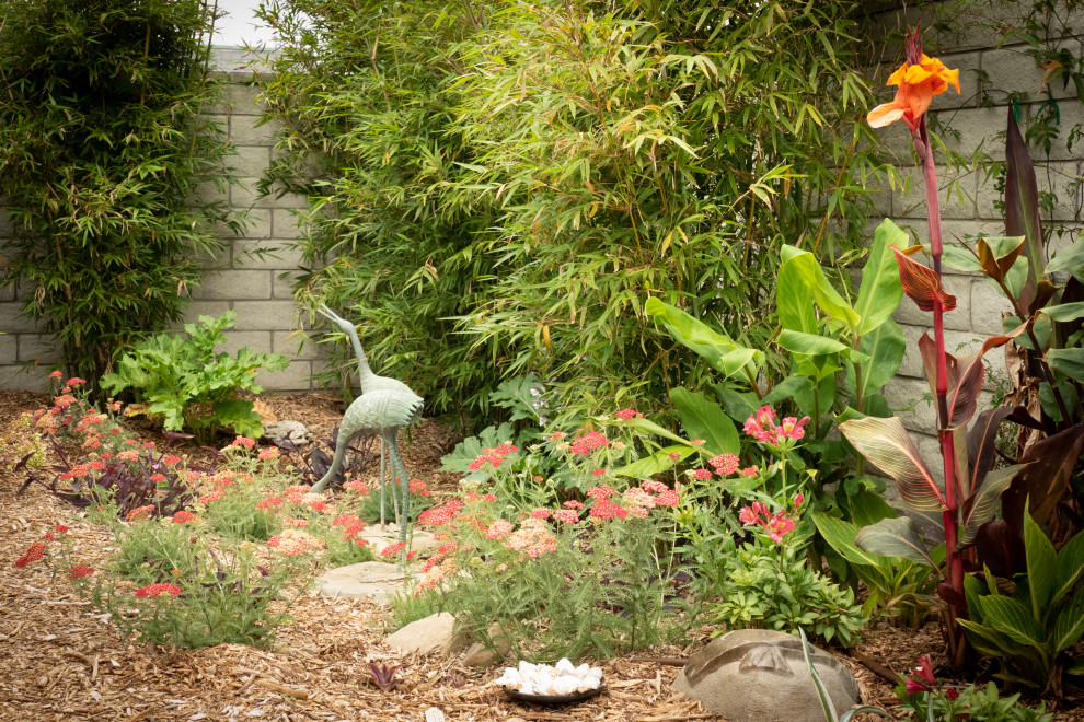 This is an example of a mid-sized tropical drought-tolerant, privacy and partial sun side yard mulch landscaping in Santa Barbara.