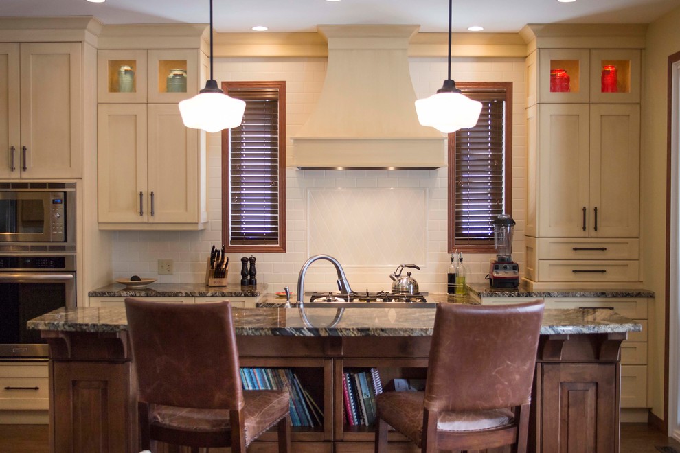 Mid-sized transitional eat-in kitchen photo with an undermount sink, recessed-panel cabinets, white cabinets, granite countertops, white backsplash, stainless steel appliances and an island