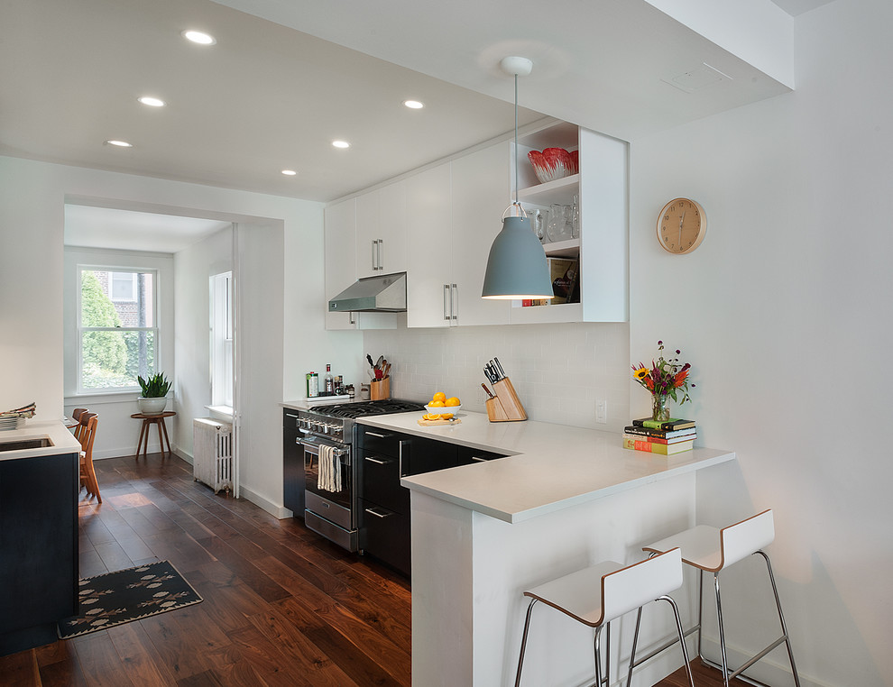 Photo of a contemporary eat-in kitchen in New York with an undermount sink, flat-panel cabinets, white cabinets, white splashback, subway tile splashback and stainless steel appliances.