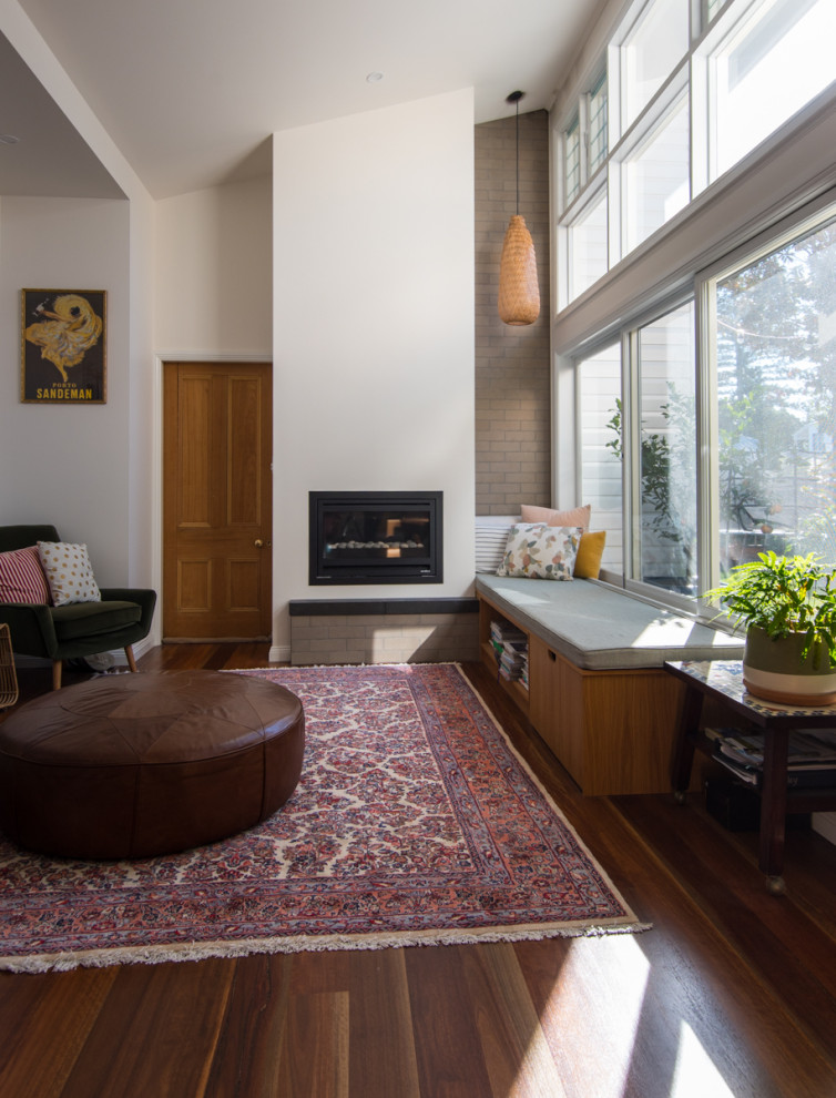 This is an example of a mid-sized traditional open concept living room in Other with white walls, medium hardwood floors, a standard fireplace, a plaster fireplace surround and brown floor.