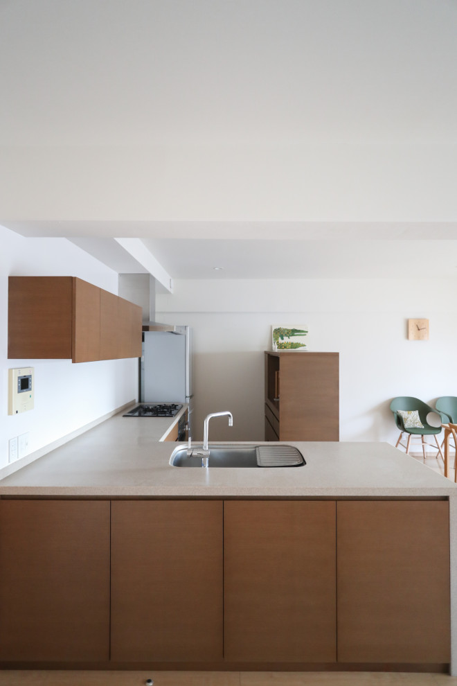 Scandinavian l-shaped open plan kitchen in Osaka with dark wood cabinets, composite countertops, white splashback, plywood flooring, brown floors, beige worktops and a wallpapered ceiling.