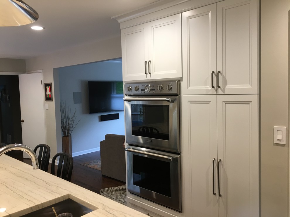 Inspiration for a large transitional u-shaped dark wood floor and brown floor open concept kitchen remodel in Chicago with an undermount sink, flat-panel cabinets, white cabinets, quartz countertops, gray backsplash, ceramic backsplash, stainless steel appliances, an island and gray countertops