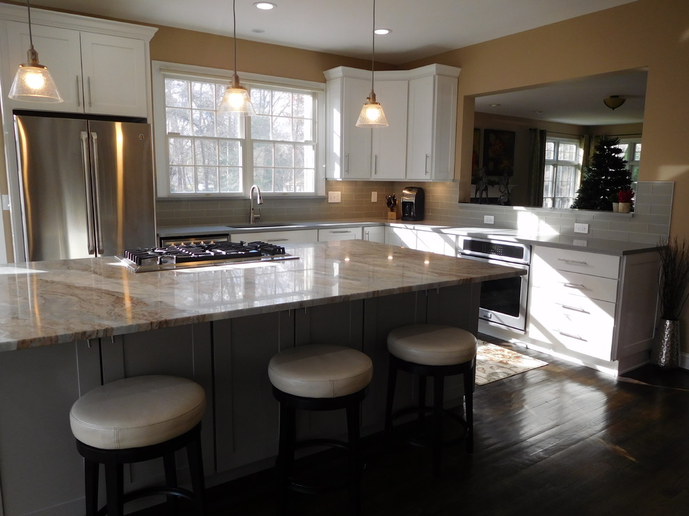 Open concept kitchen - transitional l-shaped dark wood floor open concept kitchen idea in Baltimore with a single-bowl sink, shaker cabinets, white cabinets, quartzite countertops, gray backsplash, glass tile backsplash, stainless steel appliances and an island