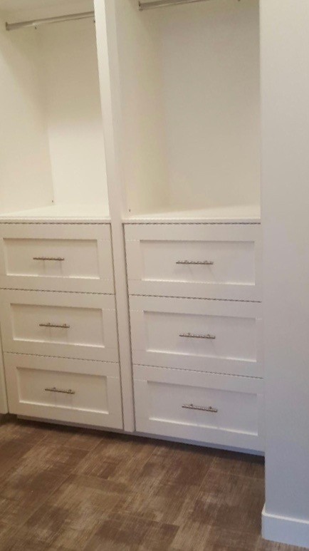 This is an example of a large modern gender-neutral walk-in wardrobe in Calgary with shaker cabinets, white cabinets and porcelain floors.
