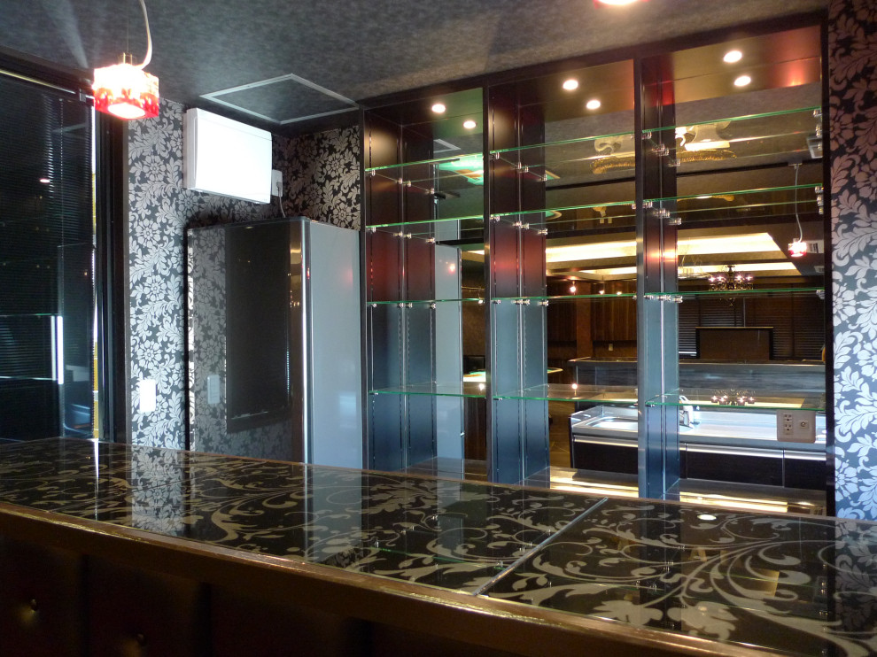東京23区にある高級な小さなエクレクティックスタイルのおしゃれなウェット バー (I型、一体型シンク、フラットパネル扉のキャビネット、茶色いキャビネット、ステンレスカウンター、茶色いキッチンパネル、ガラス板のキッチンパネル、磁器タイルの床、茶色い床、マルチカラーのキッチンカウンター) の写真