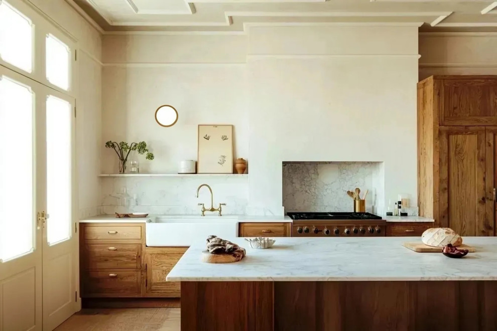 Photo of a large traditional galley open plan kitchen with a belfast sink, flat-panel cabinets, marble worktops, white splashback, marble splashback, stainless steel appliances, light hardwood flooring, an island, white worktops and a coffered ceiling.
