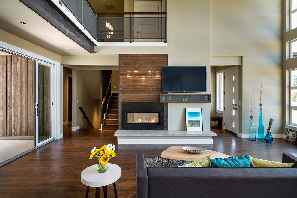 This is an example of a large contemporary open concept living room in Portland with beige walls, a two-sided fireplace, a wall-mounted tv and medium hardwood floors.