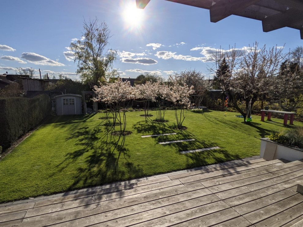 Пример оригинального дизайна: солнечный, летний регулярный сад на заднем дворе в современном стиле с клумбами, хорошей освещенностью и настилом