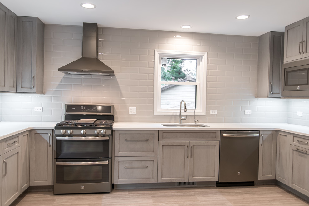 Enclosed kitchen - mid-sized transitional u-shaped vinyl floor and gray floor enclosed kitchen idea in Chicago with an undermount sink, recessed-panel cabinets, gray cabinets, quartzite countertops, gray backsplash, subway tile backsplash and stainless steel appliances