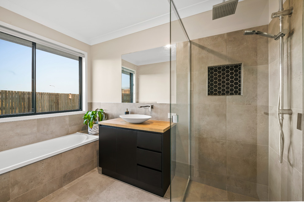 Inspiration for a contemporary master bathroom in Other with flat-panel cabinets, black cabinets, a drop-in tub, a curbless shower, a vessel sink, wood benchtops, grey floor, an open shower and brown benchtops.