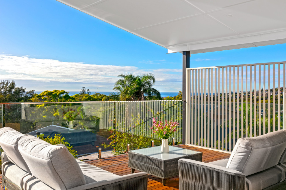 Design ideas for a medium sized beach style private glass railing balcony in Sydney with a roof extension.