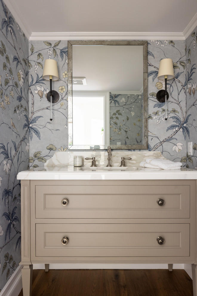 Inspiration for a classic cloakroom in Orange County with recessed-panel cabinets, beige cabinets, multi-coloured tiles, multi-coloured walls, dark hardwood flooring, a submerged sink, brown floors, white worktops, a freestanding vanity unit and wallpapered walls.