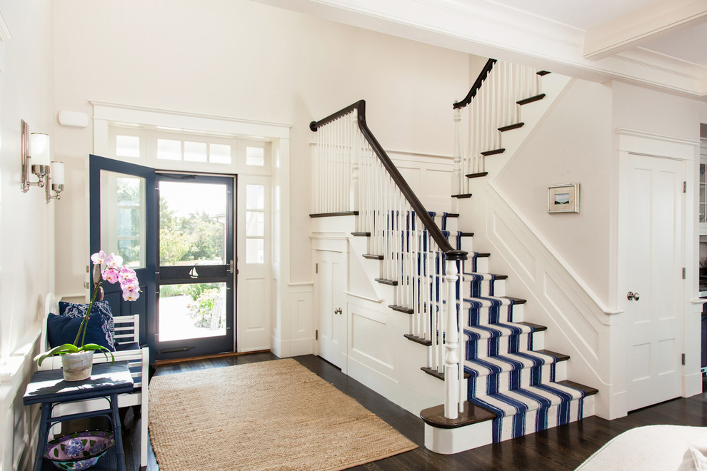 This is an example of a beach style front door in Boston with white walls, dark hardwood floors and a blue front door.