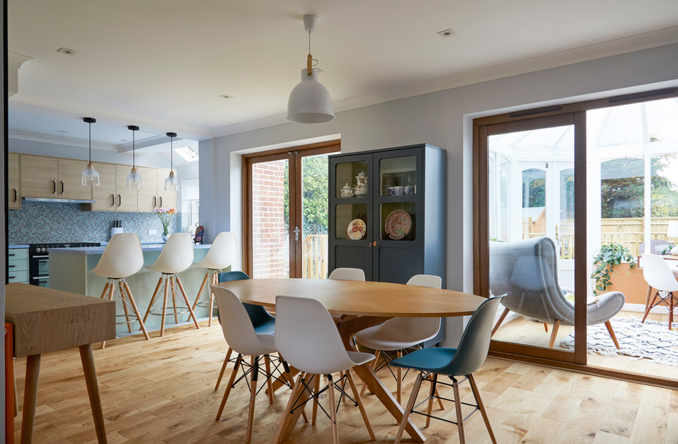 Photo of a transitional kitchen/dining combo in London with blue walls, light hardwood floors and beige floor.