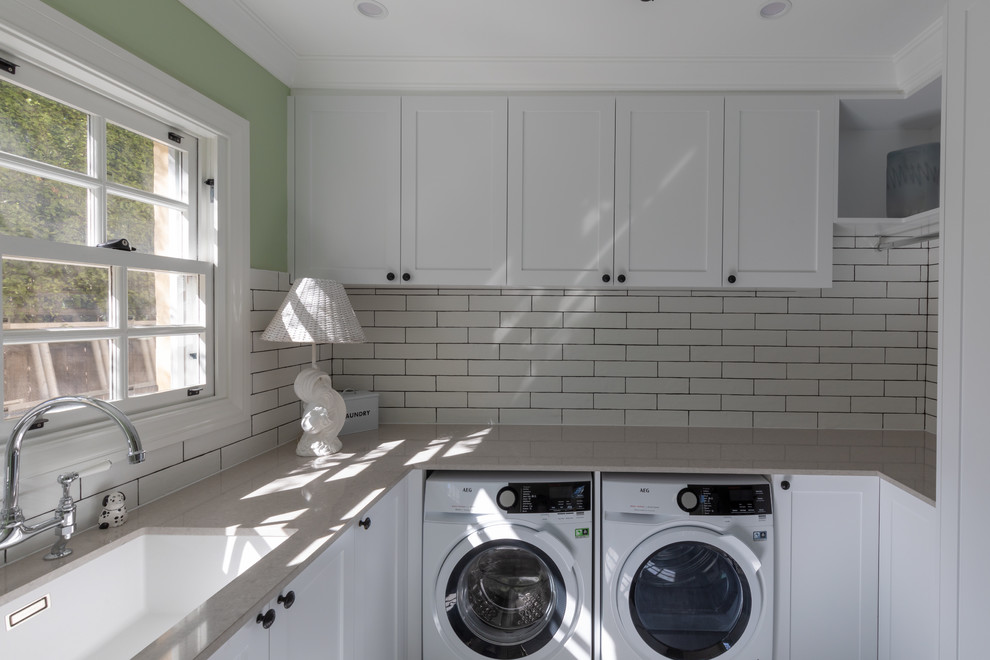 Photo of a mid-sized traditional l-shaped dedicated laundry room in Canberra - Queanbeyan with an undermount sink, shaker cabinets, white cabinets, quartz benchtops, green walls, a side-by-side washer and dryer and beige benchtop.