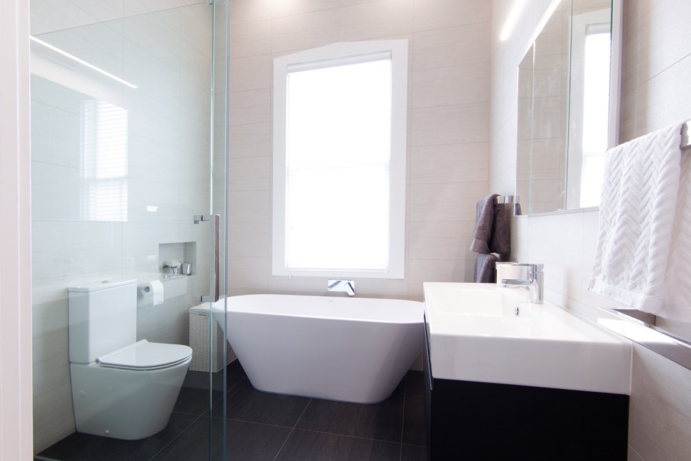 Medium sized contemporary ensuite bathroom in Sydney with freestanding cabinets, black cabinets, a corner shower, beige tiles, stone tiles, an integrated sink, solid surface worktops, black floors, a hinged door, white worktops, a single sink and a floating vanity unit.