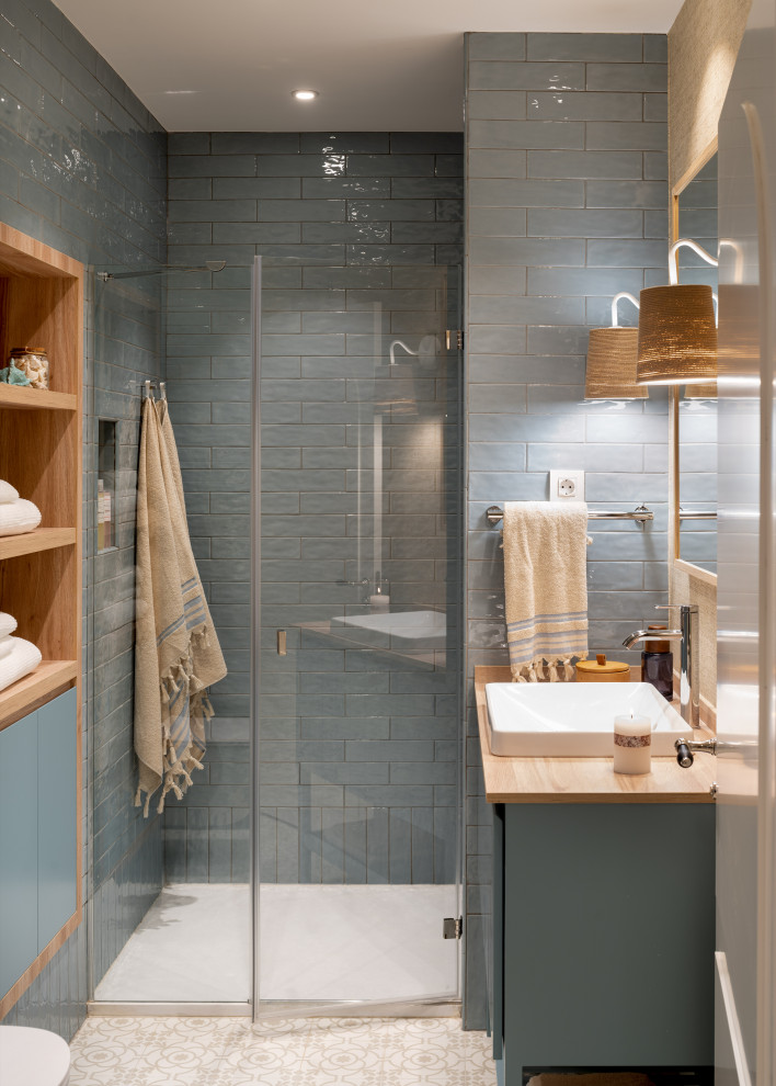 Photo of a mid-sized scandinavian master bathroom in Bilbao with white cabinets, a curbless shower, a wall-mount toilet, blue tile, ceramic tile, ceramic floors, a vessel sink, laminate benchtops, a hinged shower door, brown benchtops, a niche, a single vanity, a built-in vanity, blue walls, beige floor and flat-panel cabinets.