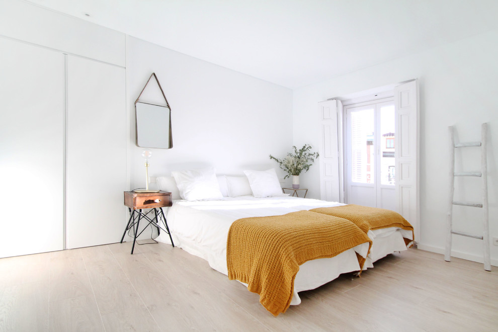 Mid-sized contemporary guest bedroom in Madrid with white walls and medium hardwood floors.