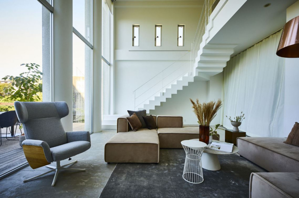 This is an example of a large contemporary formal open concept living room in Manchester with white walls and concrete floors.