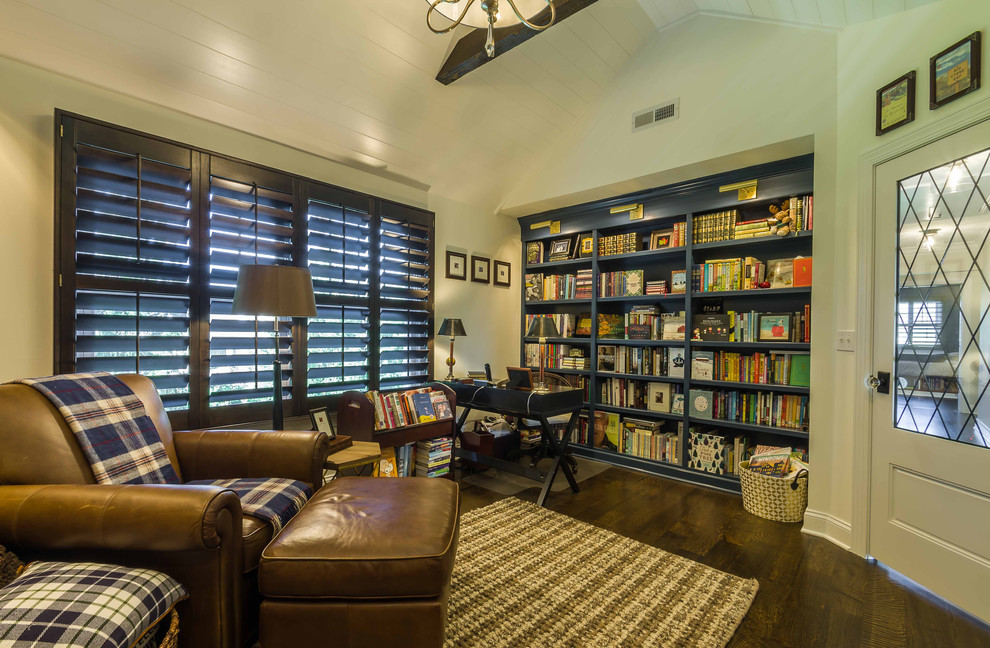 Photo of a mid-sized traditional home office in Chicago with a library, white walls, dark hardwood floors, a freestanding desk, brown floor, exposed beam, no fireplace, a brick fireplace surround and wallpaper.