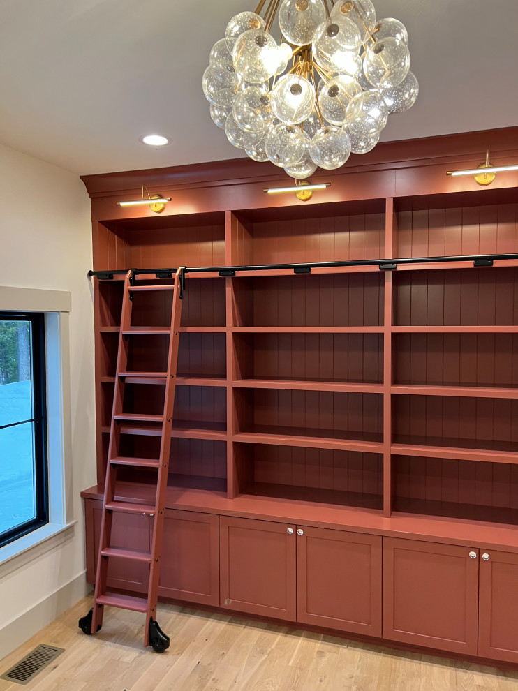 Photo of a mid-sized transitional home office in Other with a library, beige walls and light hardwood floors.
