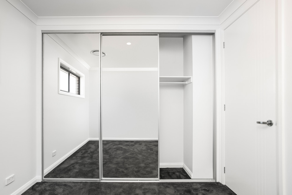 Photo of a mid-sized contemporary gender-neutral built-in wardrobe in Sydney with white cabinets, carpet and black floor.