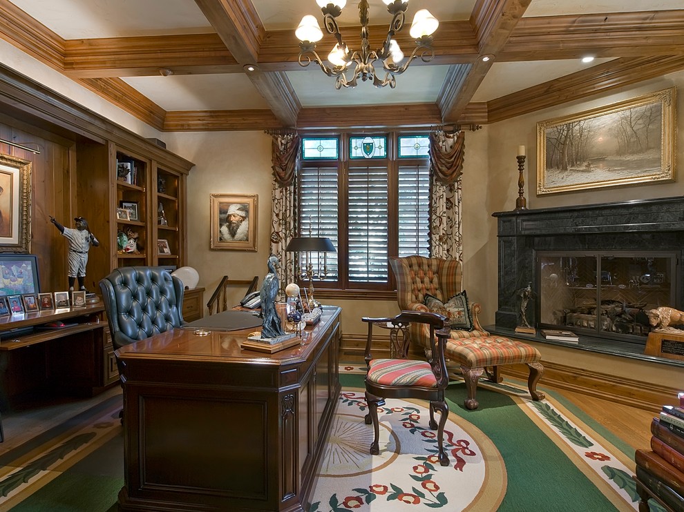 This is an example of a large traditional study room in Denver with beige walls, a standard fireplace, a stone fireplace surround, a freestanding desk and dark hardwood floors.