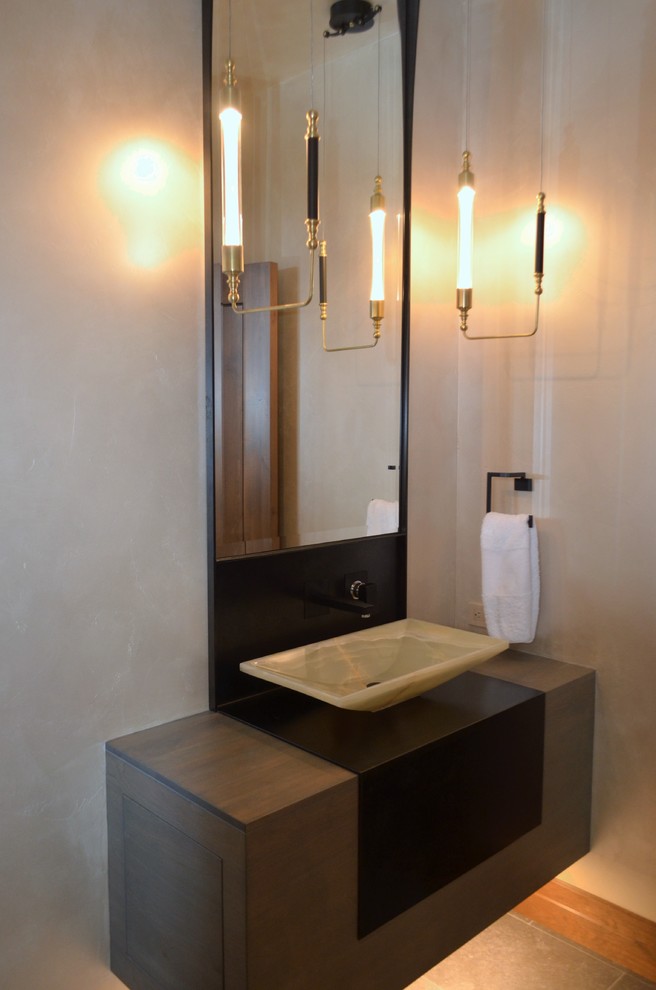 Small industrial powder room in Seattle with flat-panel cabinets, medium wood cabinets, a one-piece toilet, multi-coloured walls, limestone floors, a vessel sink, wood benchtops and grey floor.