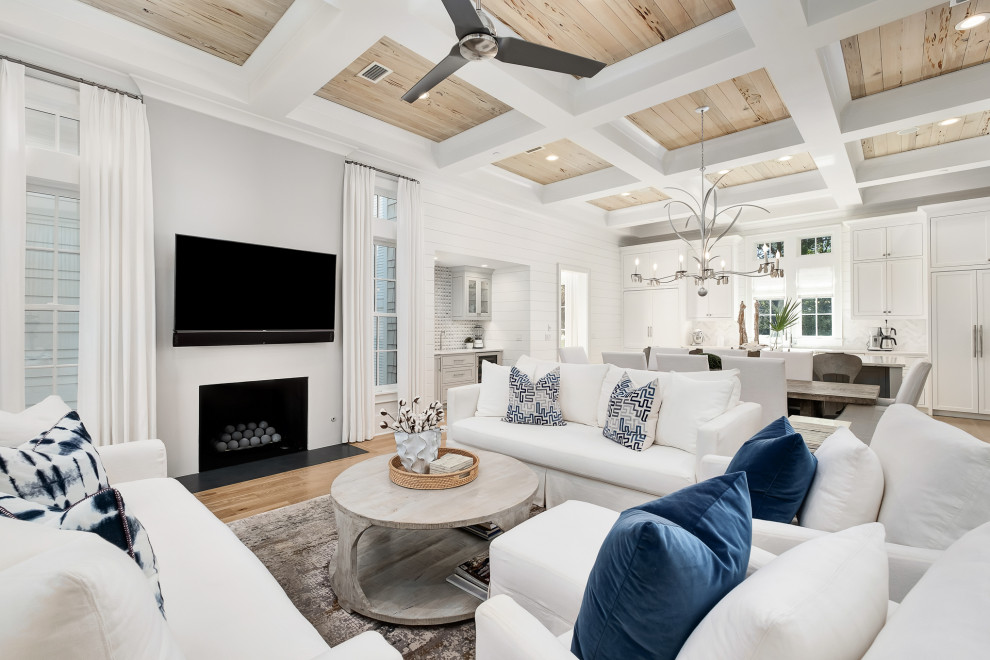 Photo of a large beach style formal open concept living room in Other with white walls, medium hardwood floors, a standard fireplace, a wall-mounted tv, brown floor, coffered and planked wall panelling.