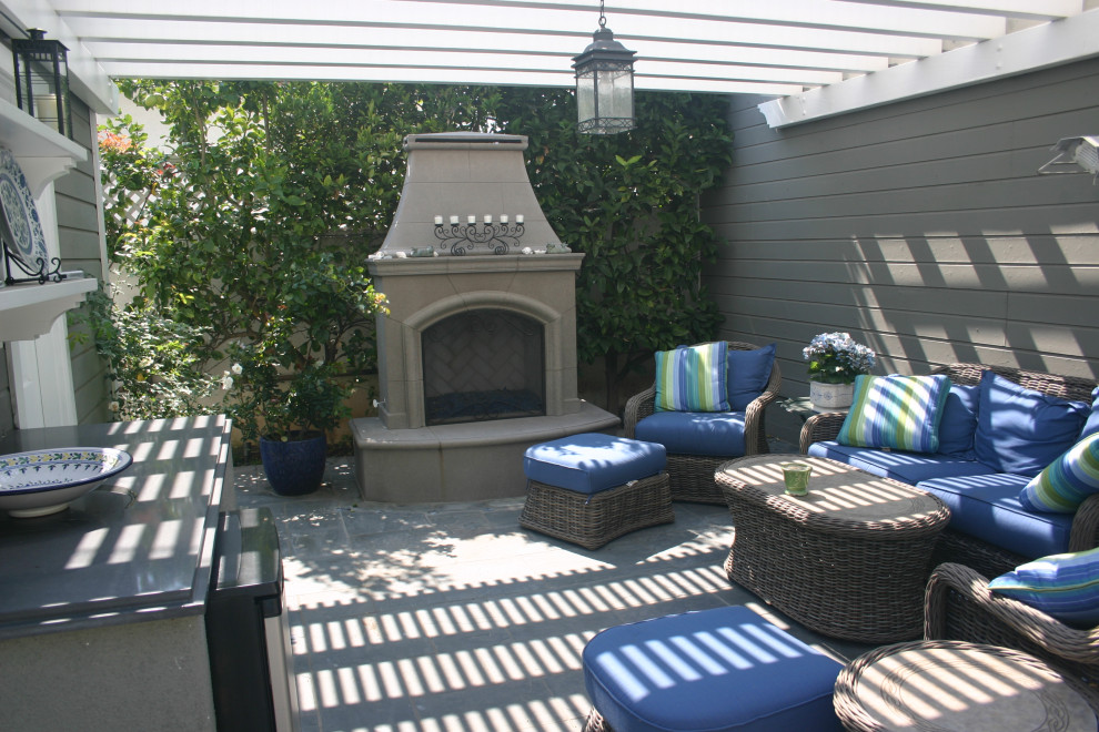 Small traditional backyard patio in Los Angeles with with fireplace, natural stone pavers and a pergola.