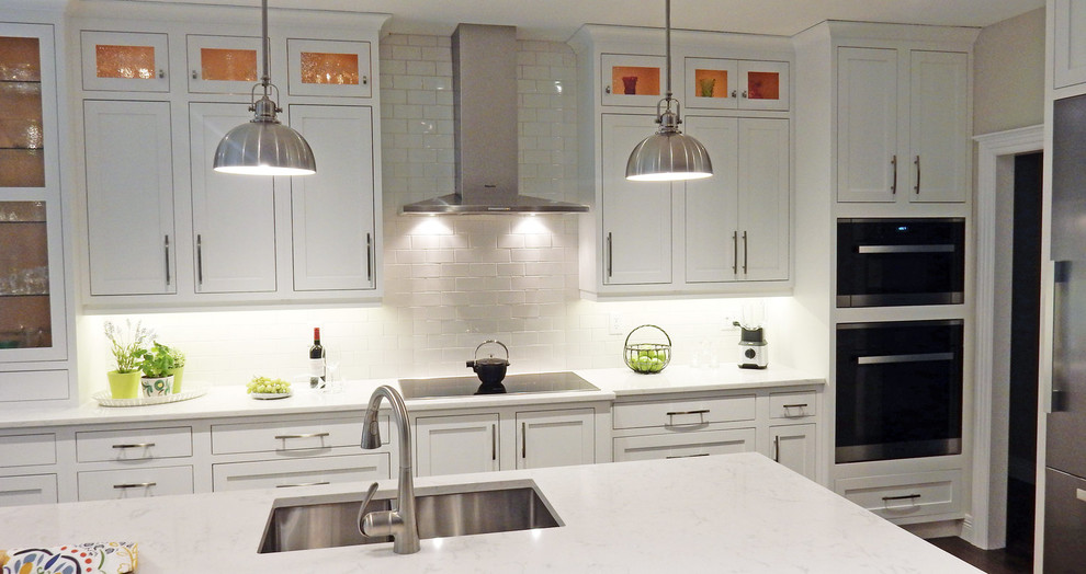 Inspiration for a mid-sized transitional l-shaped dark wood floor and brown floor open concept kitchen remodel with a double-bowl sink, beaded inset cabinets, white cabinets, quartz countertops, white backsplash, glass tile backsplash, stainless steel appliances, an island and white countertops
