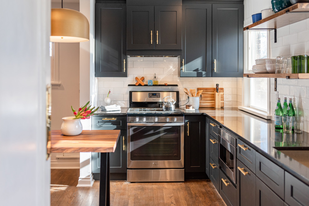 Enclosed kitchen - small contemporary galley dark wood floor and brown floor enclosed kitchen idea in Denver with an undermount sink, shaker cabinets, black cabinets, quartzite countertops, white backsplash, ceramic backsplash, stainless steel appliances, a peninsula and black countertops