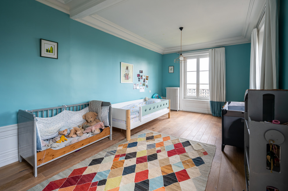 Ejemplo de dormitorio infantil de 1 a 3 años contemporáneo grande con paredes azules, suelo de madera clara, suelo marrón y vigas vistas