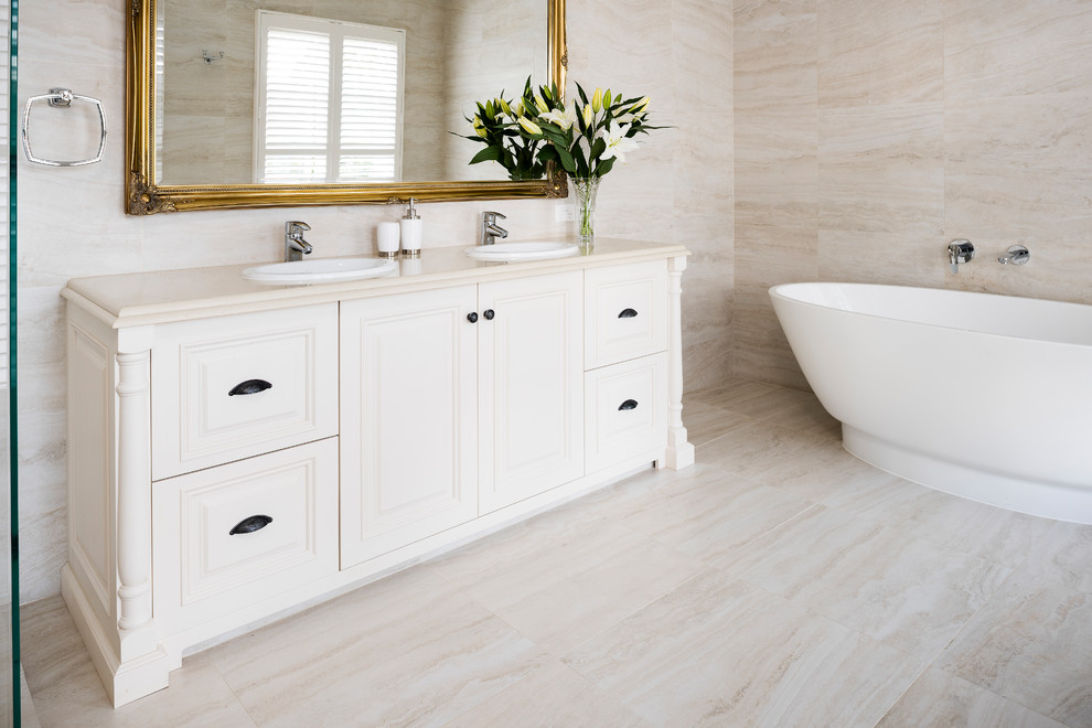 Inspiration for a small traditional master bathroom in Melbourne with furniture-like cabinets, white cabinets, a freestanding tub, a curbless shower, a two-piece toilet, white tile, ceramic tile, white walls, ceramic floors, a drop-in sink, engineered quartz benchtops, white floor and a hinged shower door.