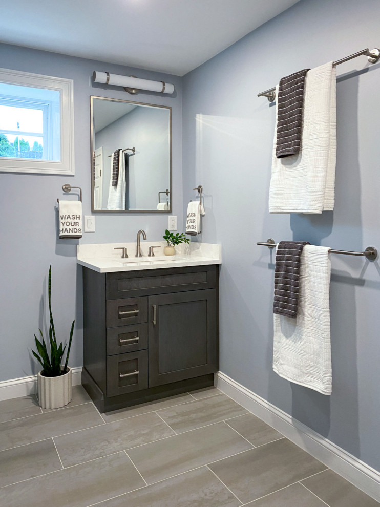 Example of a transitional white tile and ceramic tile porcelain tile, gray floor and single-sink corner shower design in Boston with shaker cabinets, gray cabinets, a one-piece toilet, gray walls, an undermount sink, quartz countertops, a hinged shower door, white countertops and a built-in vanity