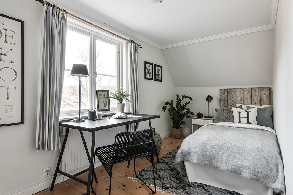 Photo of a small scandinavian bedroom in Stockholm with white walls, light hardwood floors and no fireplace.