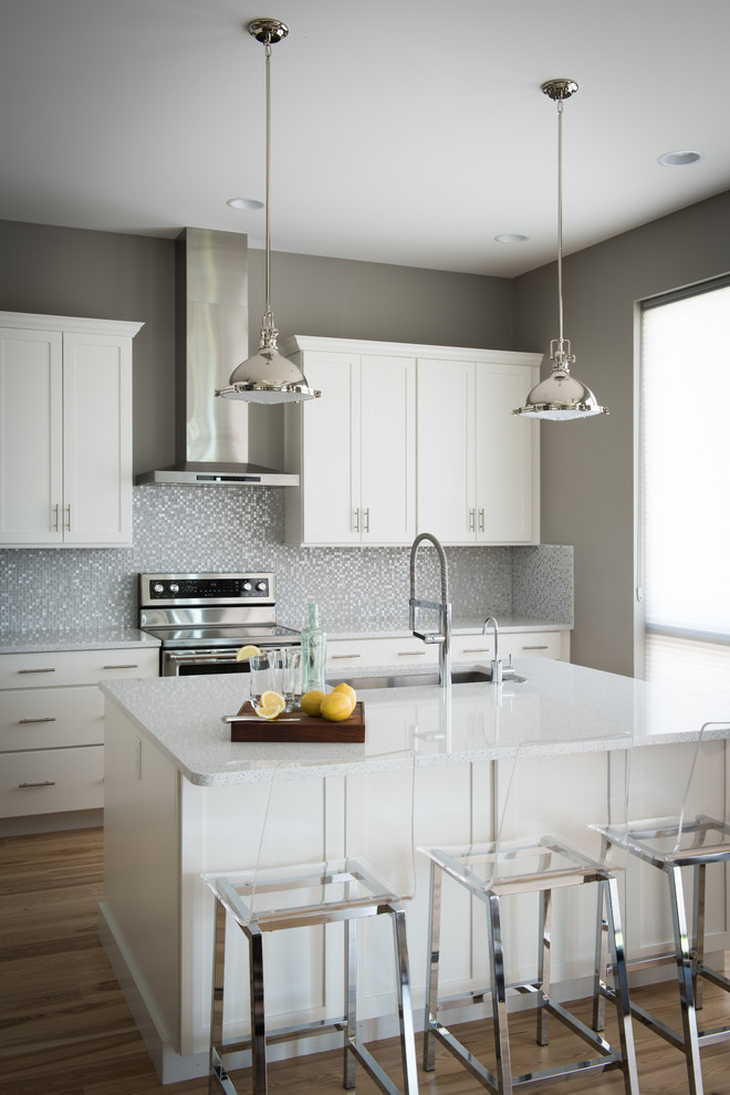 Inspiration for a mid-sized transitional l-shaped light wood floor open concept kitchen remodel with an undermount sink, shaker cabinets, white cabinets, quartz countertops, multicolored backsplash, glass tile backsplash, stainless steel appliances and an island