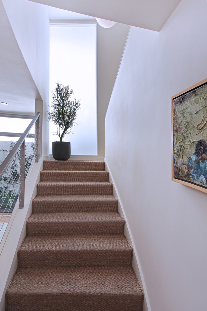 Photo of a mid-sized contemporary carpeted u-shaped staircase in Orange County with carpet risers and cable railing.
