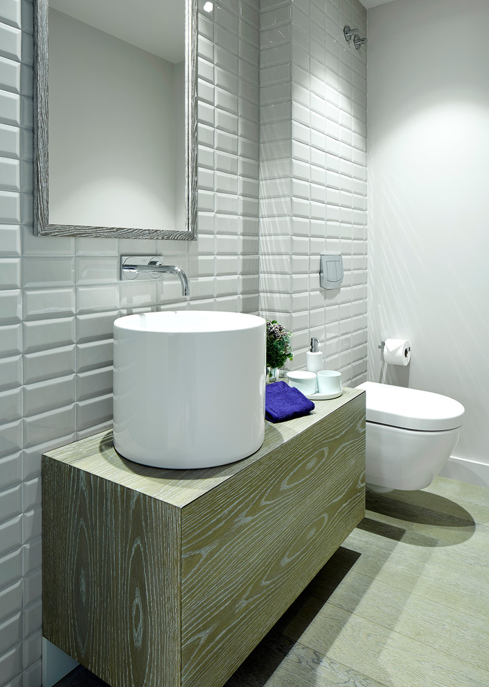 Mid-sized contemporary powder room in Barcelona with flat-panel cabinets, medium wood cabinets, a wall-mount toilet, white walls, medium hardwood floors and a vessel sink.