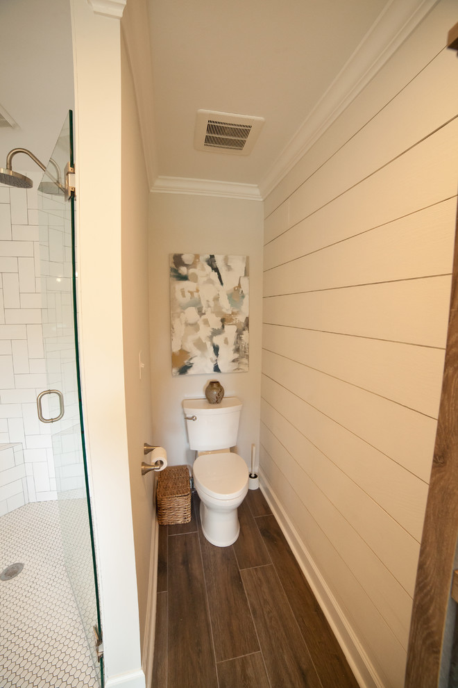 Photo of a large modern master bathroom in Atlanta with furniture-like cabinets, white cabinets, a corner shower, a one-piece toilet, white tile, subway tile, grey walls, dark hardwood floors, an undermount sink, marble benchtops, brown floor and a hinged shower door.