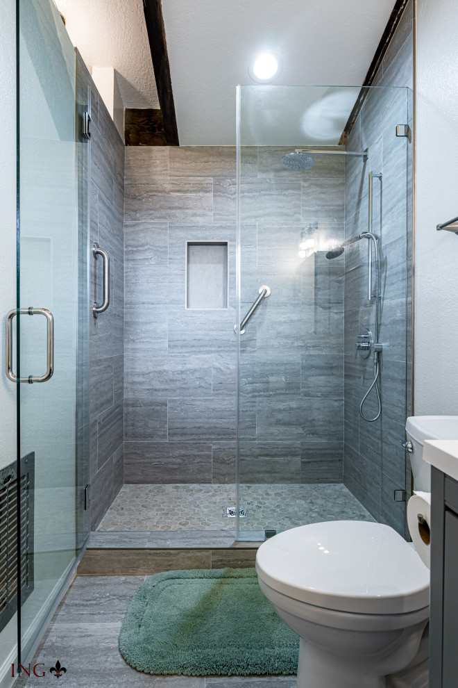 Cette image montre une salle de bain design de taille moyenne avec un placard à porte plane, des portes de placard grises, WC séparés, un carrelage gris, des carreaux de céramique, un mur blanc, un sol en carrelage de céramique, un lavabo posé, un plan de toilette en quartz modifié, un sol gris, une cabine de douche à porte battante, un plan de toilette blanc, une niche, meuble simple vasque, meuble-lavabo encastré et un plafond voûté.